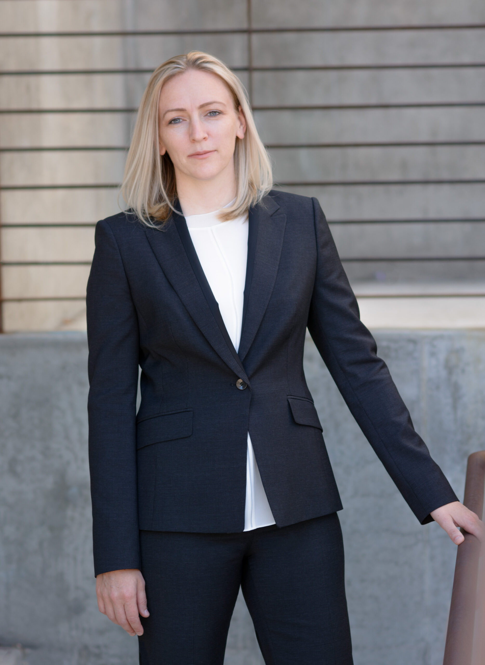 Woman in blue sweater leaning against wooden beam in modern office.
